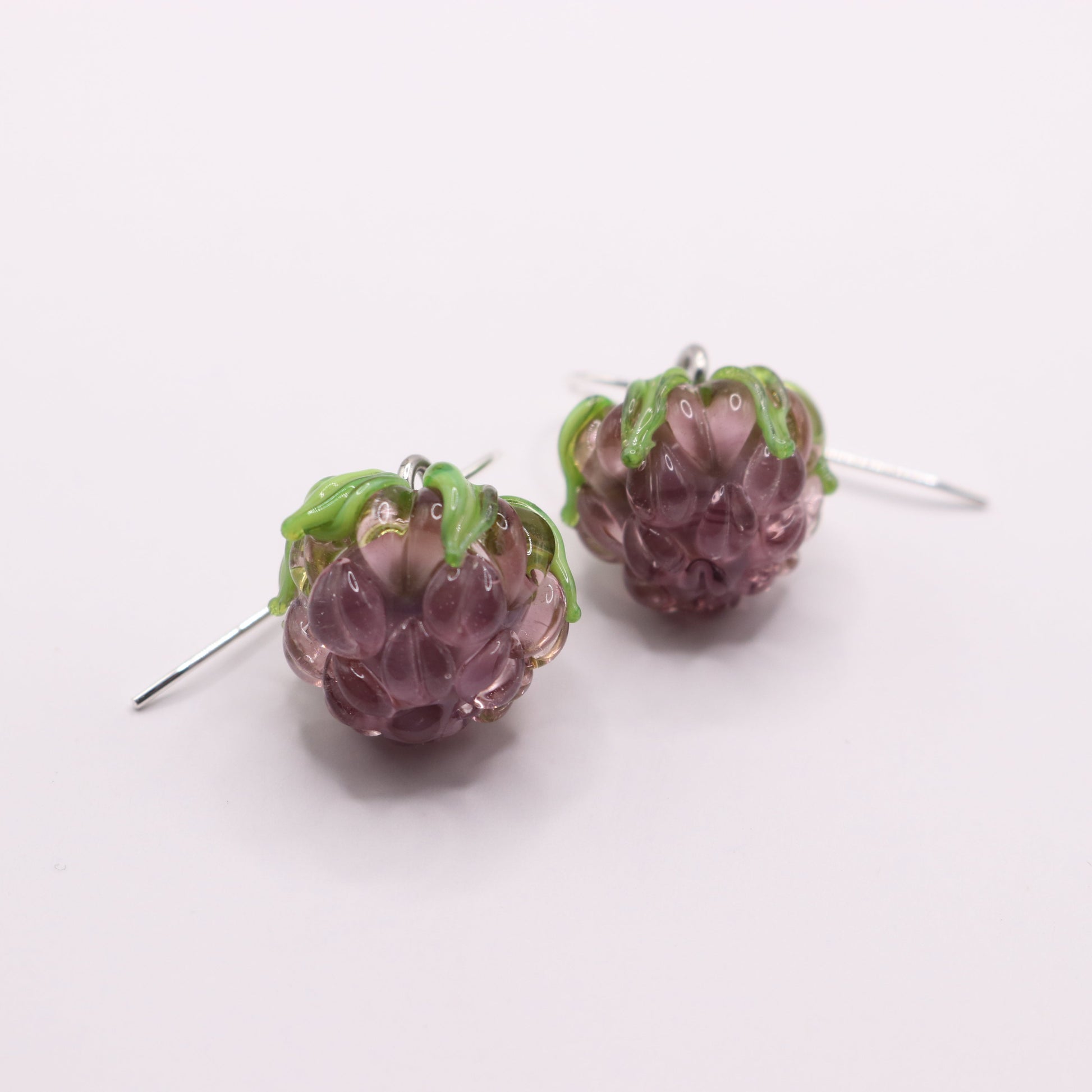 Pair of purple berry-shaped earrings on a white background